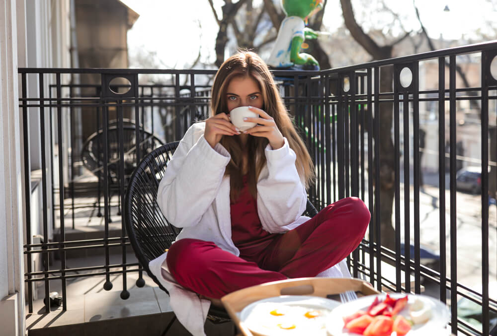 ベランダでコーヒーと食事をする女性