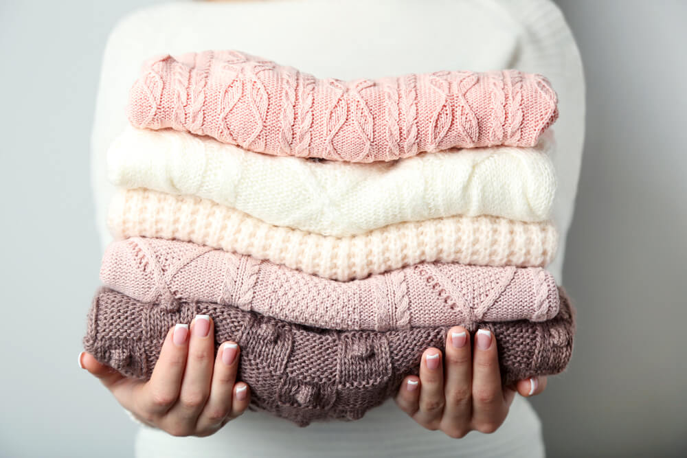 畳んだニットセーターを持つ女性