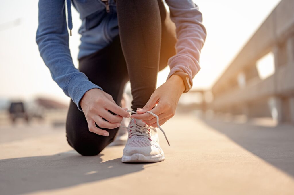 ジョギング中に靴紐をむずぶ女性