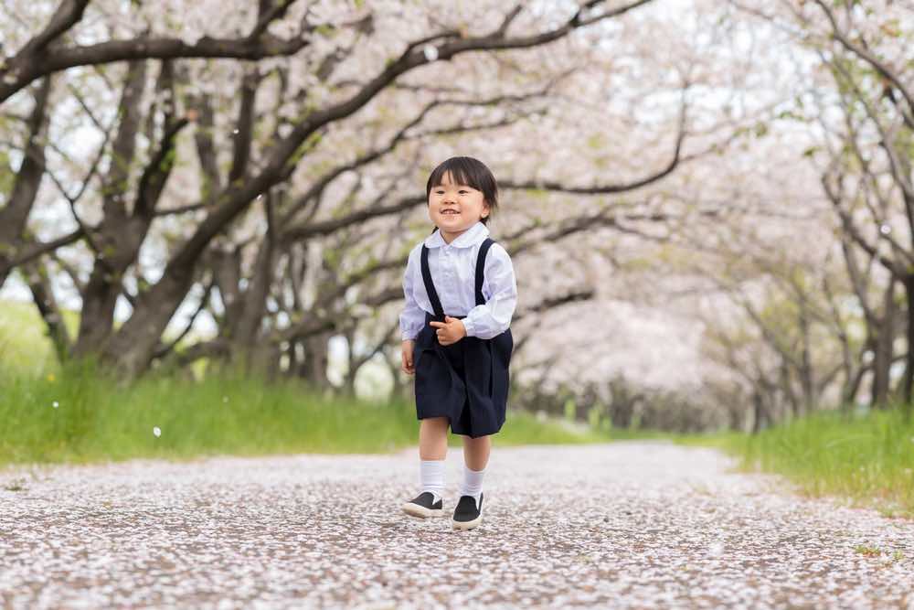 桜並木と制服を着た園児