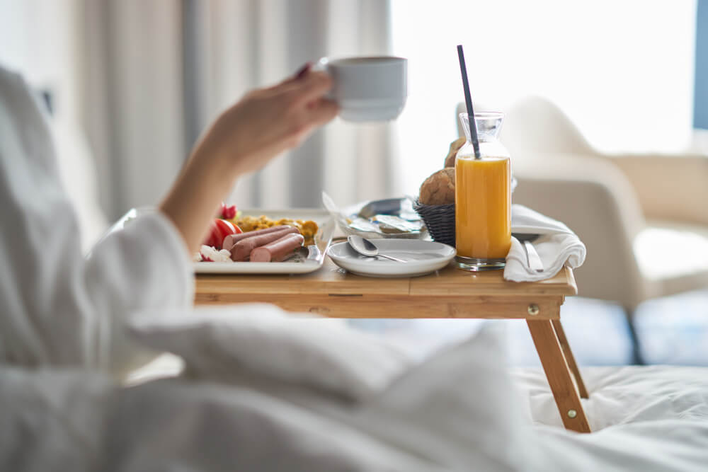 ホテルの部屋で朝食を食べる女性