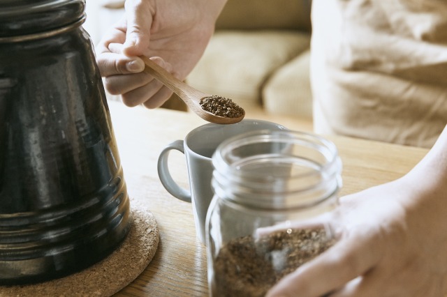 インスタントコーヒーの粉をスプーンでコップに入れる人